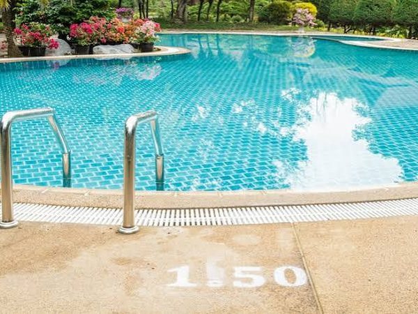 Piscina con gresite azul, escalera de acero inoxidable y jardín