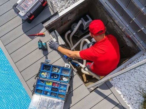 Técnico reparando la instalación de filtración en la arqueta de una piscina