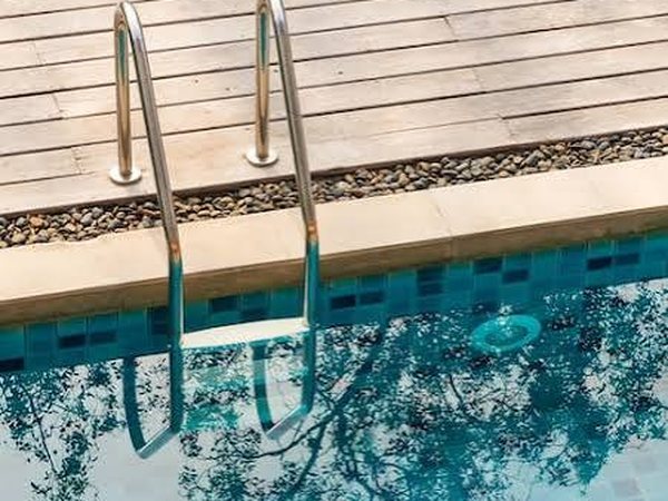 Escalera de acero y coronación de una piscina con revestimiento cerámico